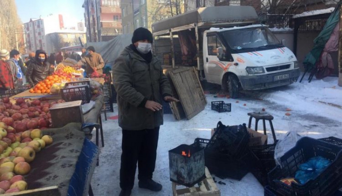 Pazarcılar soğuk havada açık alana kurdukları soba ile ısınıyor
